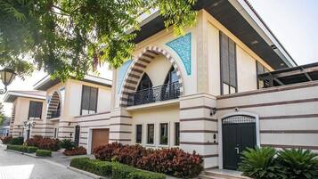 Um edifício moderno com telhado plano, janelas amplas e uma varanda com guarda-corpo.
