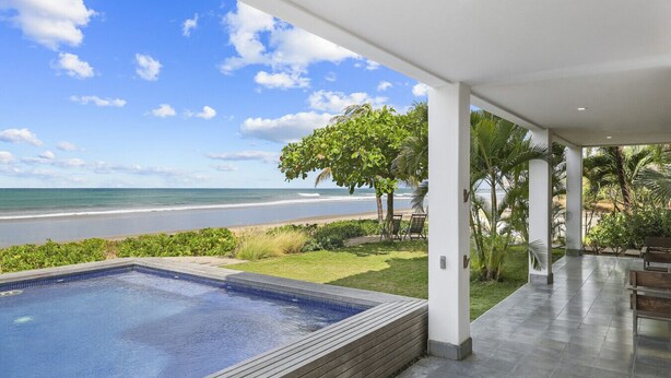 A modern pool area with a view of the beach and ocean. - Iguana Beach House: Spacious Beachfront House with Swimming Pool (Hacienda Iguana)