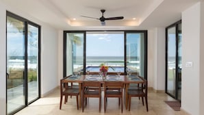 A dining area with a table set for six, large glass doors, and a view of the ocean. - Iguana Beach House: Spacious Beachfront House with Swimming Pool (Hacienda Iguana)