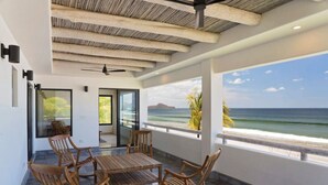 A modern room with a wooden ceiling, a dining table with chairs, and a view of the ocean. - Iguana Beach House: Spacious Beachfront House with Swimming Pool (Hacienda Iguana)