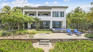 A two-story modern house with a swimming pool, lounge chairs, and tropical landscaping. - Iguana Beach House: Spacious Beachfront House with Swimming Pool (Hacienda Iguana)