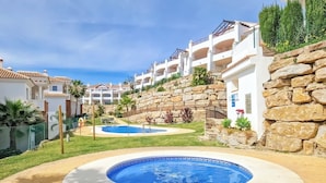 A resort with a swimming pool, stone walls, and multiple-story buildings with balconies.