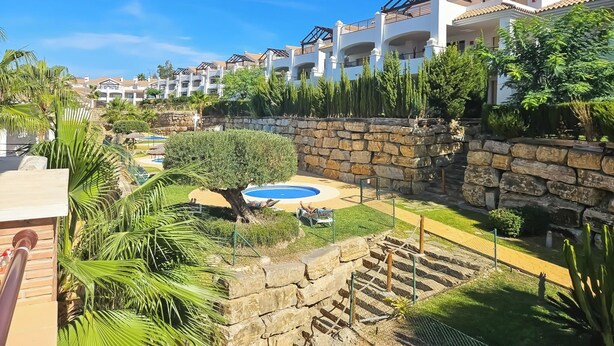 A resort with multiple white buildings, a swimming pool, and lush greenery.