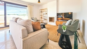 A modern living room with a sofa, a coffee table, a TV, and a bookshelf.