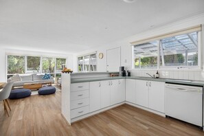 A modern kitchen with white cabinetry, a wooden countertop, and a large window. - Allure Beach House Rye. (Rye)