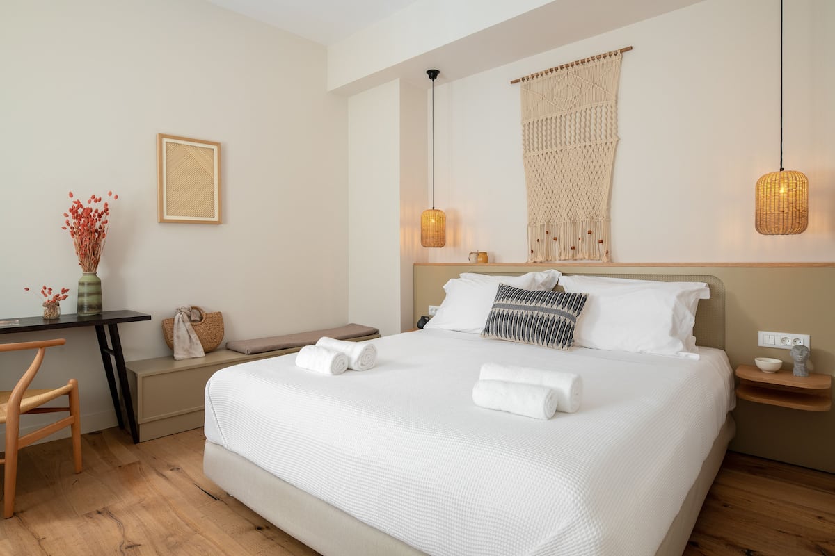 A neatly arranged hotel room with a large bed, bedside tables, a desk, and a chair.