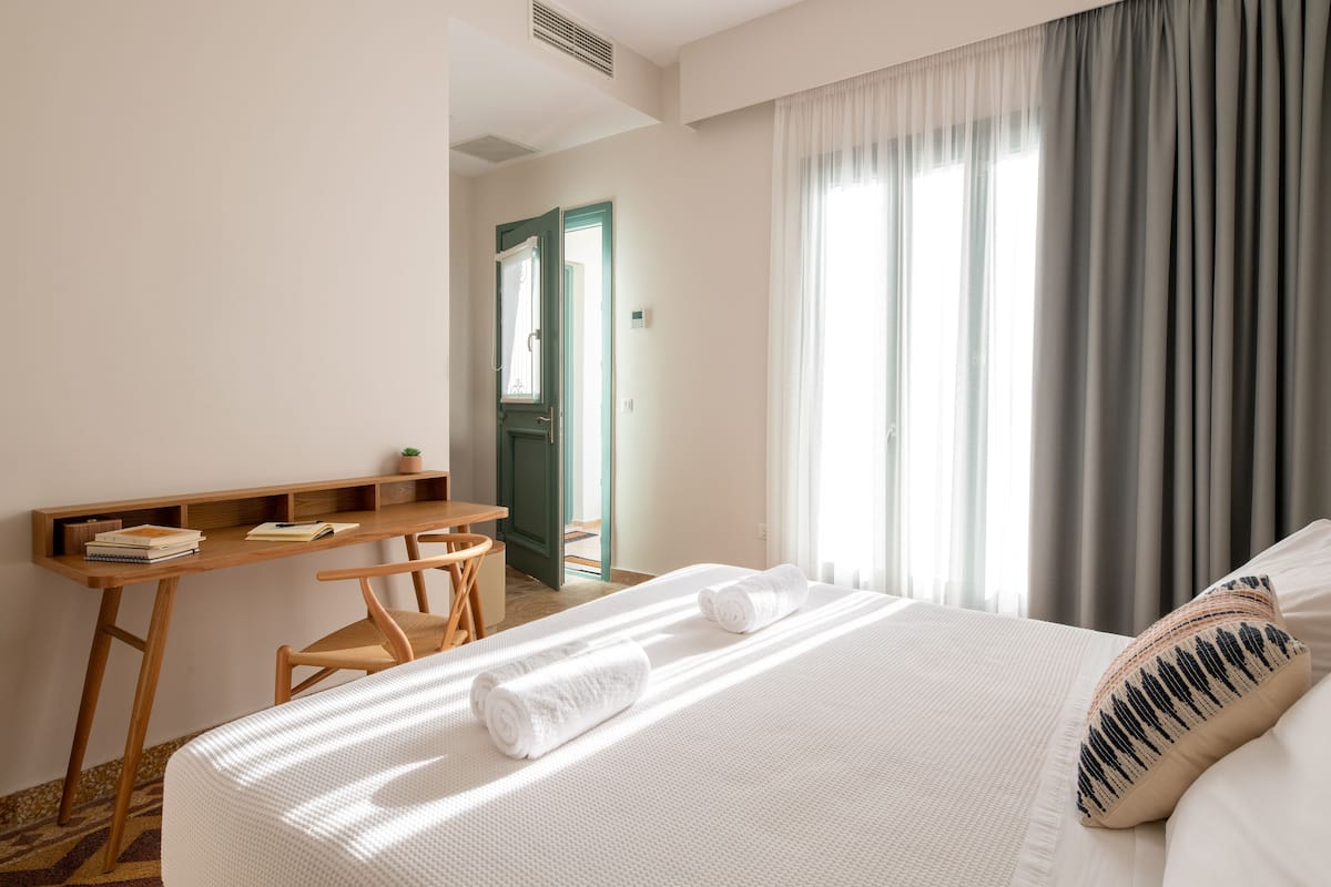 A hotel room with a bed, a desk, and a chair.