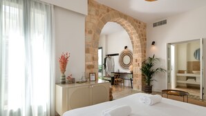 A hotel room with a large bed, a desk, a mirror, and a stone archway. - Casa Natura (Rhodes)