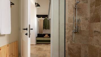 Une salle de bain avec une douche, un porte-serviettes et un banc sur lequel est posé un chapeau.
