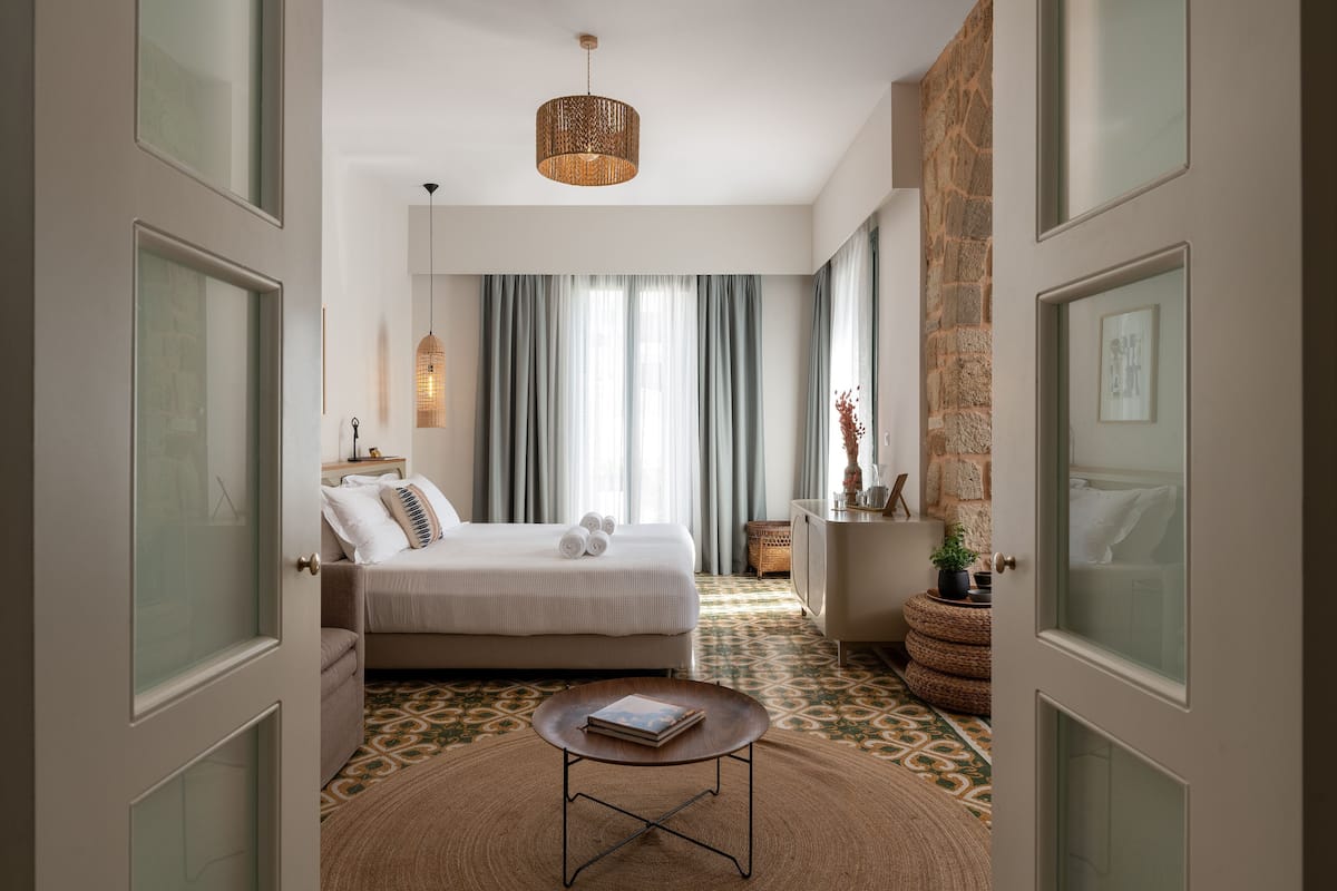 A bedroom with a bed, a bedside table, a hanging light fixture, and a patterned floor.