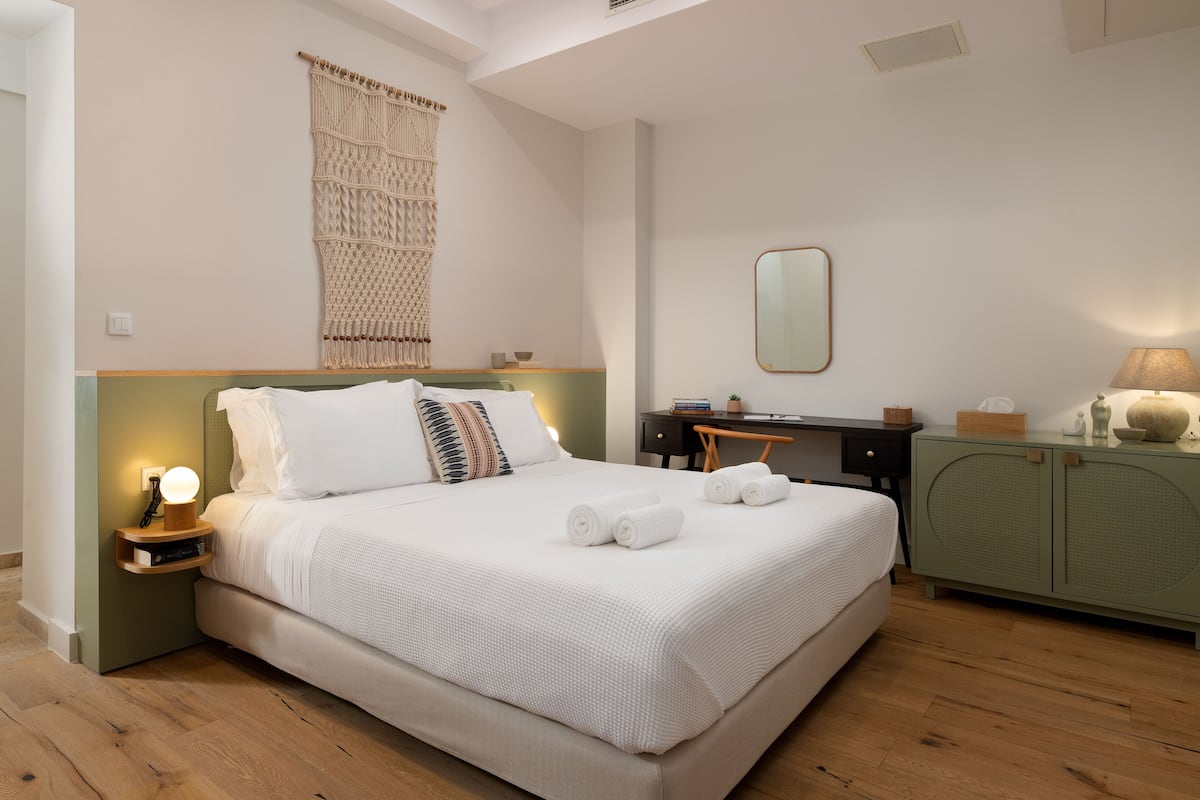 A neatly arranged bedroom with a bed, bedside table, lamp, and a green cabinet.