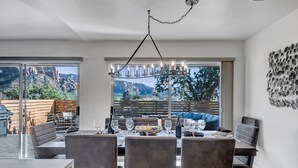 A dining area with a table set for four, a chandelier, and a view of mountains through large windows. - Prime Location, Walk To Restaurants, Enjoy The Sunrise And Red Rock Views (Sedona)