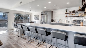 A modern kitchen with a large island, bar stools, stainless steel appliances, and a view of the outdoors. - Prime Location, Walk To Restaurants, Enjoy The Sunrise And Red Rock Views (Sedona)