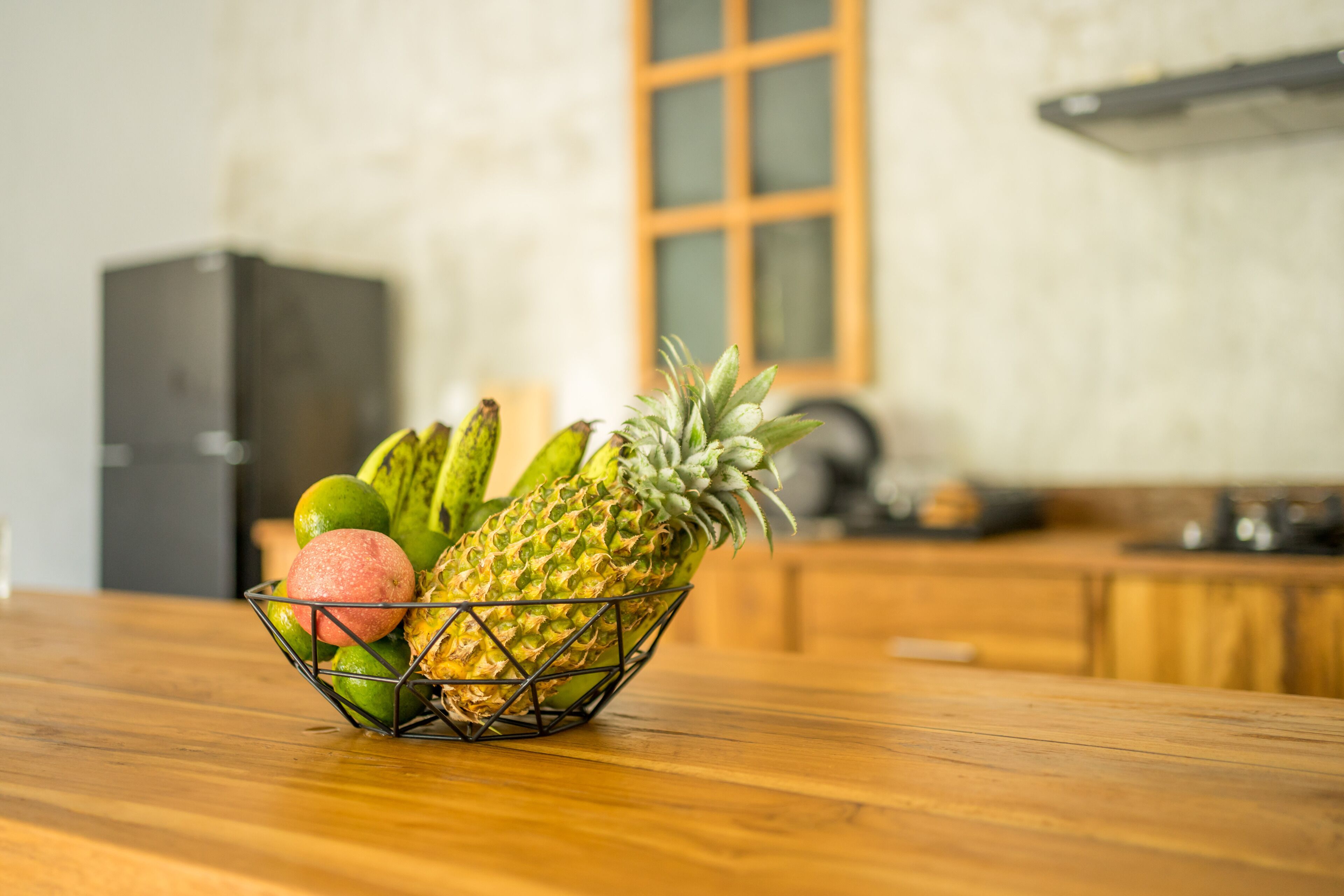 Eine Obstschale auf einem Holztisch, im Hintergrund eine Küche.