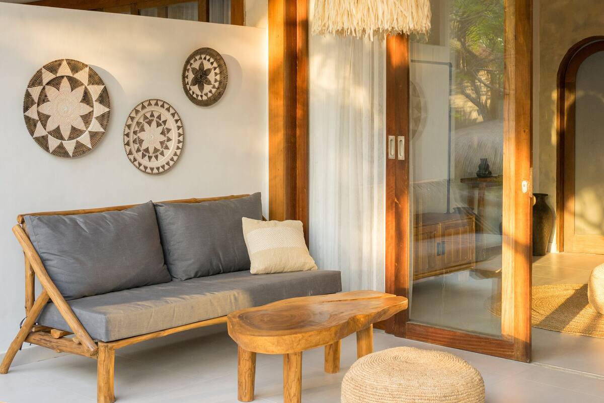 Una sala moderna con sofá, mesa de centro redonda de madera y lámpara colgante.