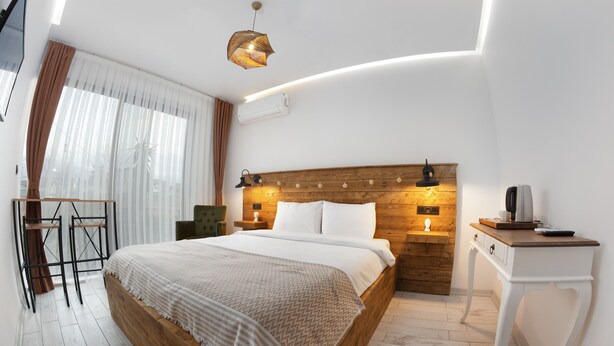 A modern hotel room with a wooden bed, a desk, and a chair. - Yiğit Pansiyon (Sapanca)