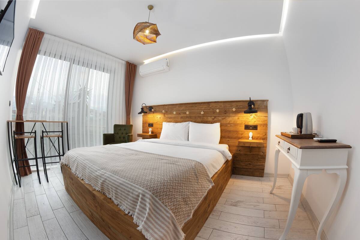A modern hotel room with a wooden bed, a desk, and a chair.
