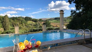 A poolside area with a view of a pool, a tiled deck, and a bowl of chips and drinks.