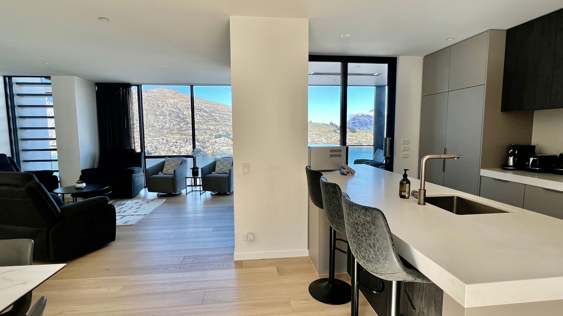 Een moderne keuken met een groot eiland, een eetgedeelte met een tafel en stoelen, en een woonkamer met een bank en salontafel.