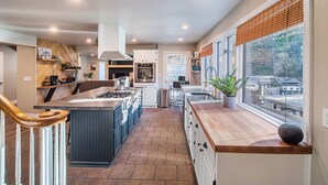 Una cocina moderna con una isla central, electrodomésticos integrados y un amplio ventanal con vistas a una terraza.