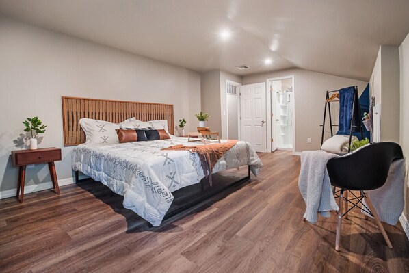 Une chambre à coucher comprenant un lit, des tables de chevet, une chaise et une armoire.