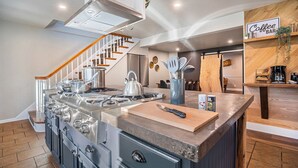 Una cocina moderna con una isla central, electrodomésticos de acero inoxidable y una zona de bar de café.