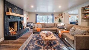 Una sala acogedora con chimenea, un sofá modular, una mesa de centro y una alfombra.