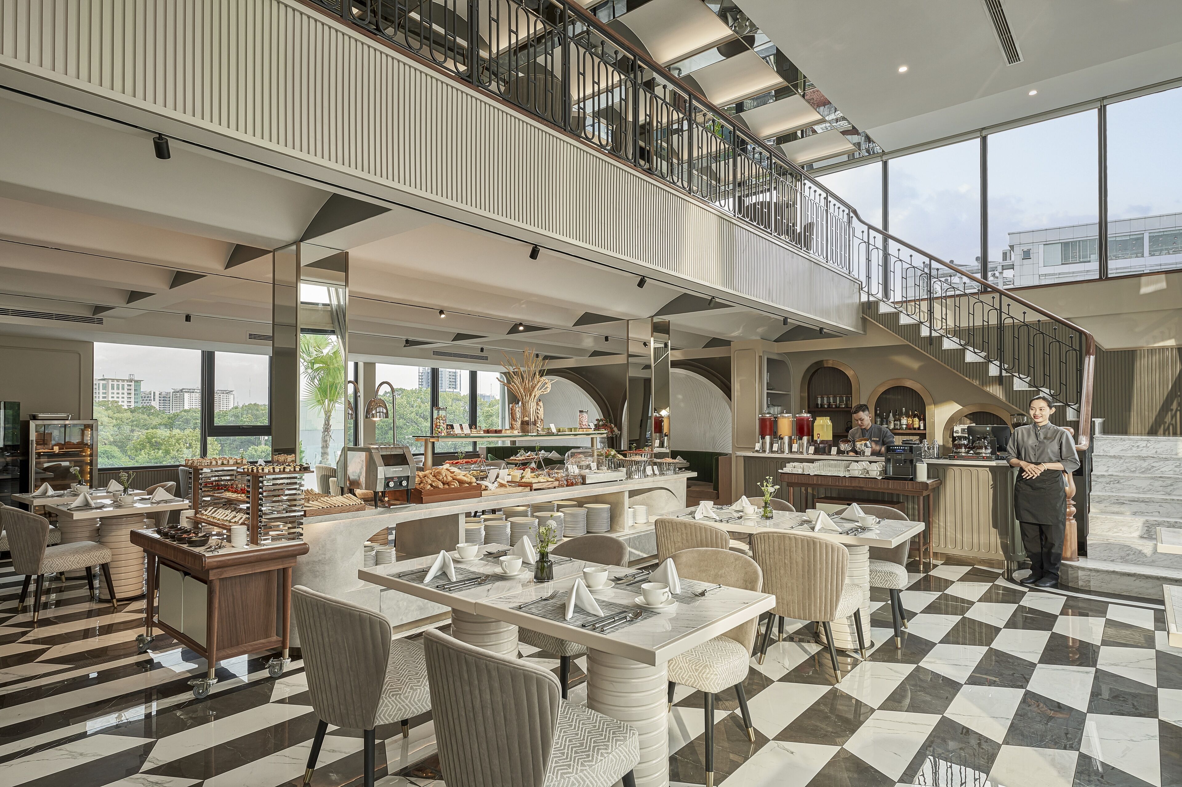 Un hall d’hôtel spacieux, doté d’un sol à carreaux, d’un espace buffet et d’un escalier menant à un étage supérieur.