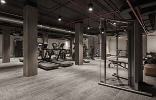 A modern gym with cardio machines, weightlifting equipment, and a mirrored wall.