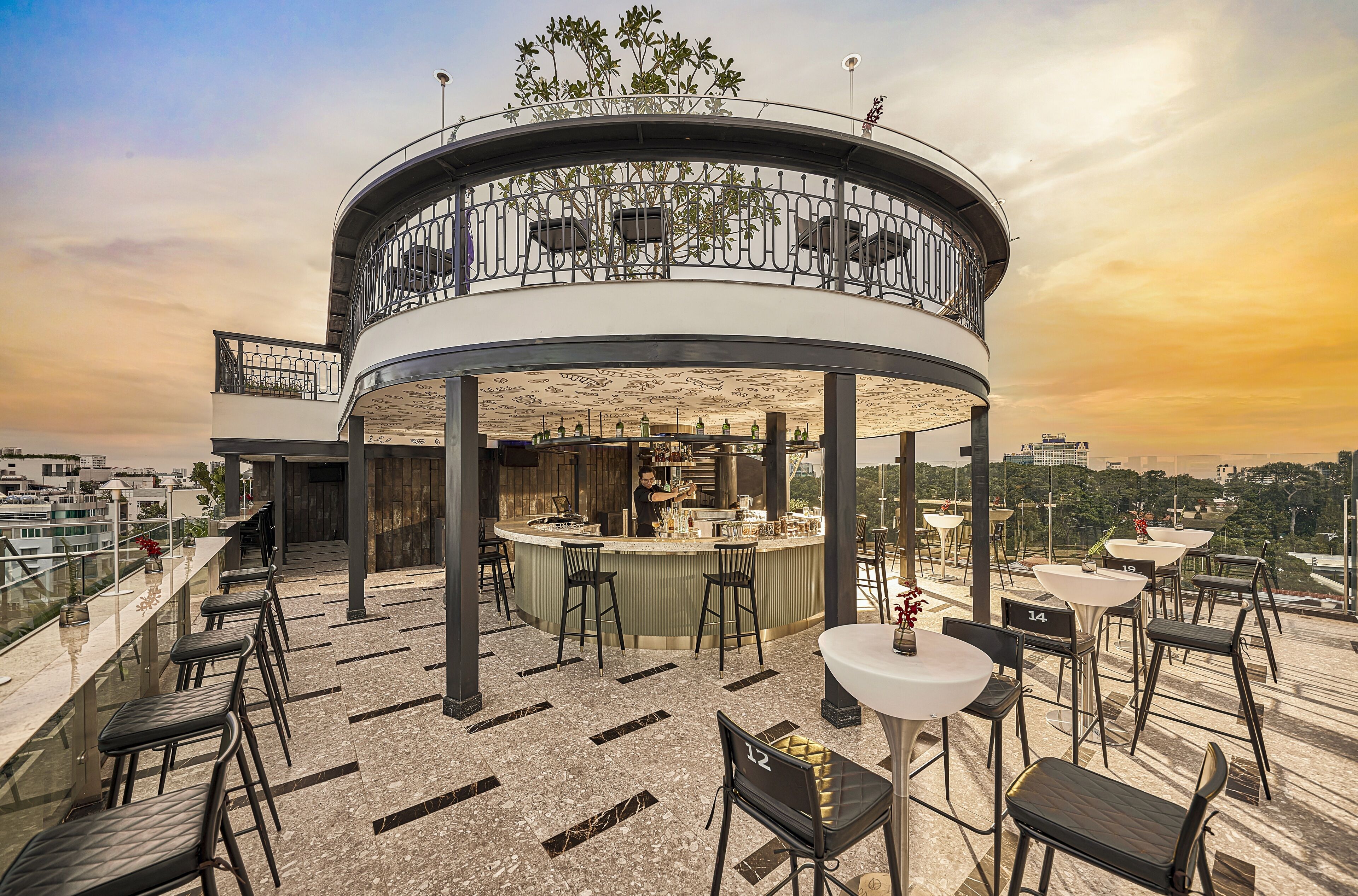 Un bar en la azotea con distribución circular, que incluye una zona de bar, asientos y vistas de la ciudad.