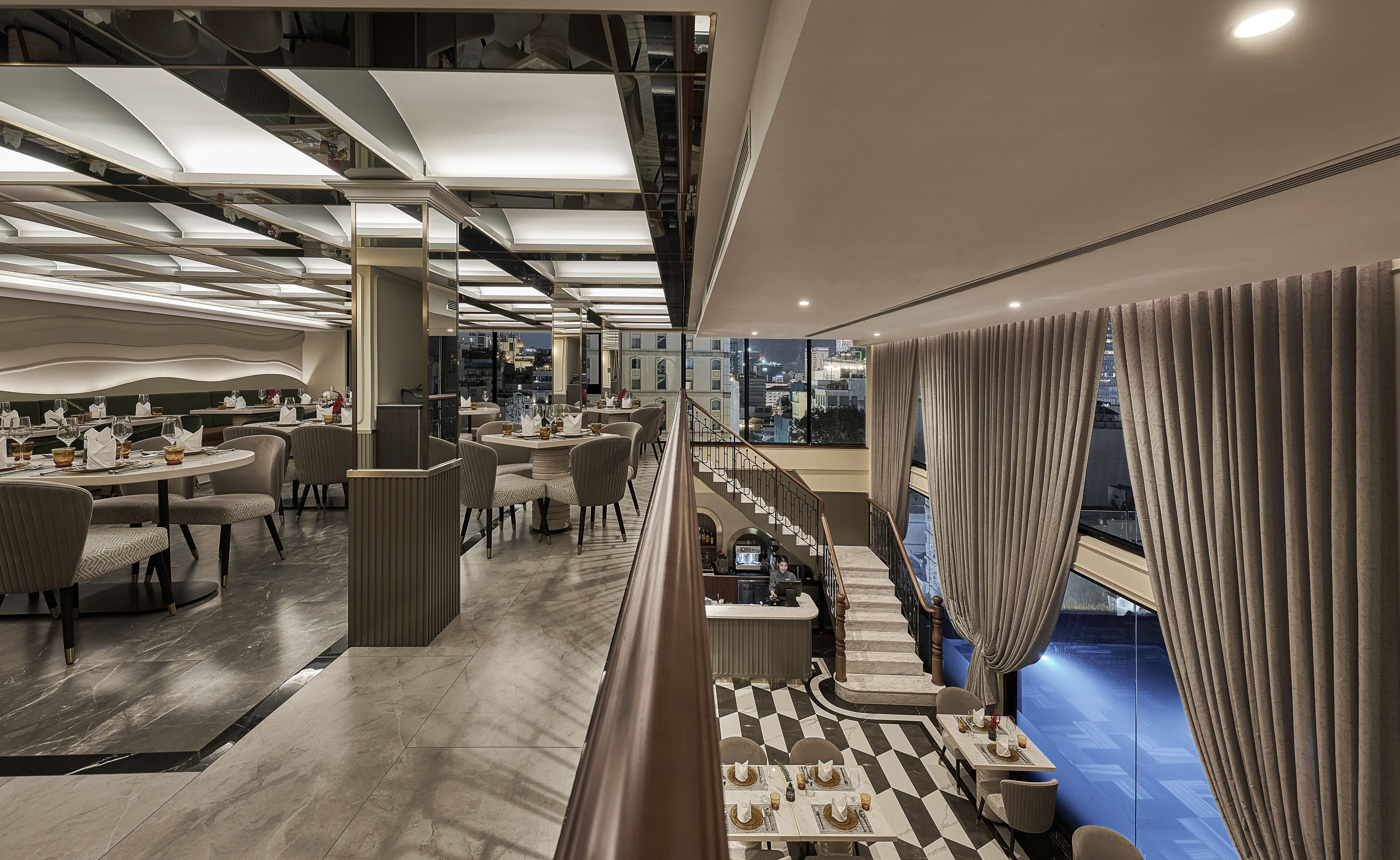 A modern restaurant with a high ceiling, exposed ductwork, and a view of the cityscape through large windows.