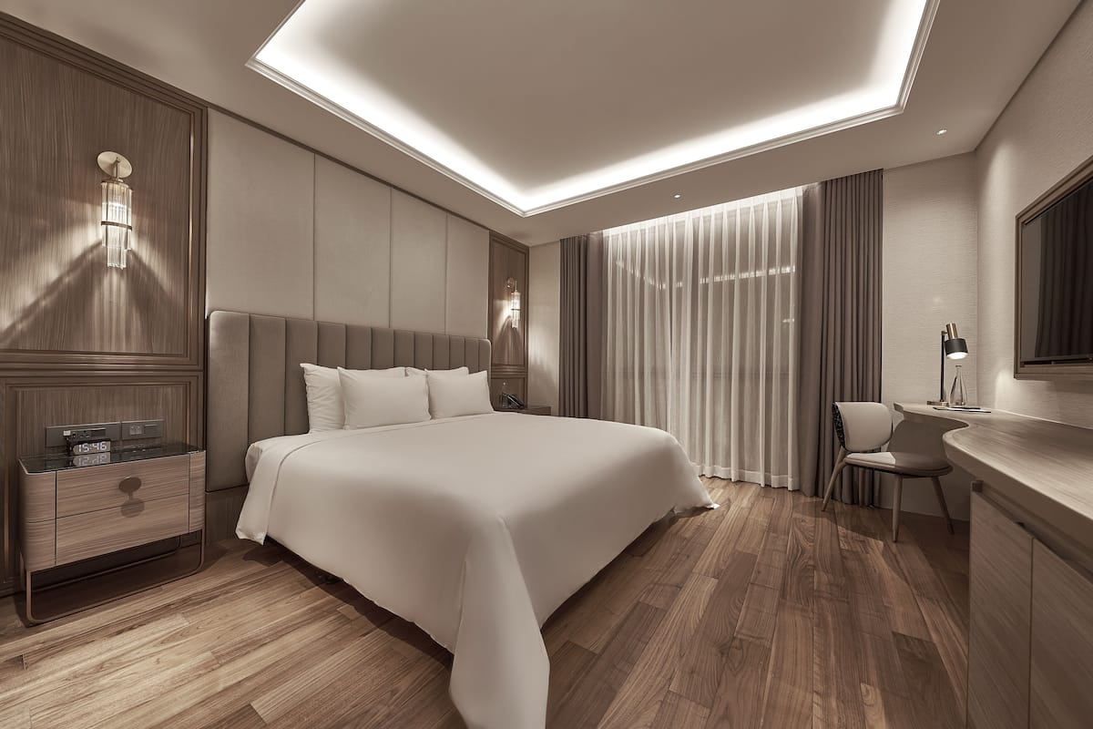 Ein modernes Hotelzimmer mit einem großen Bett, Holzboden, einem Schreibtisch und einem Spiegel.