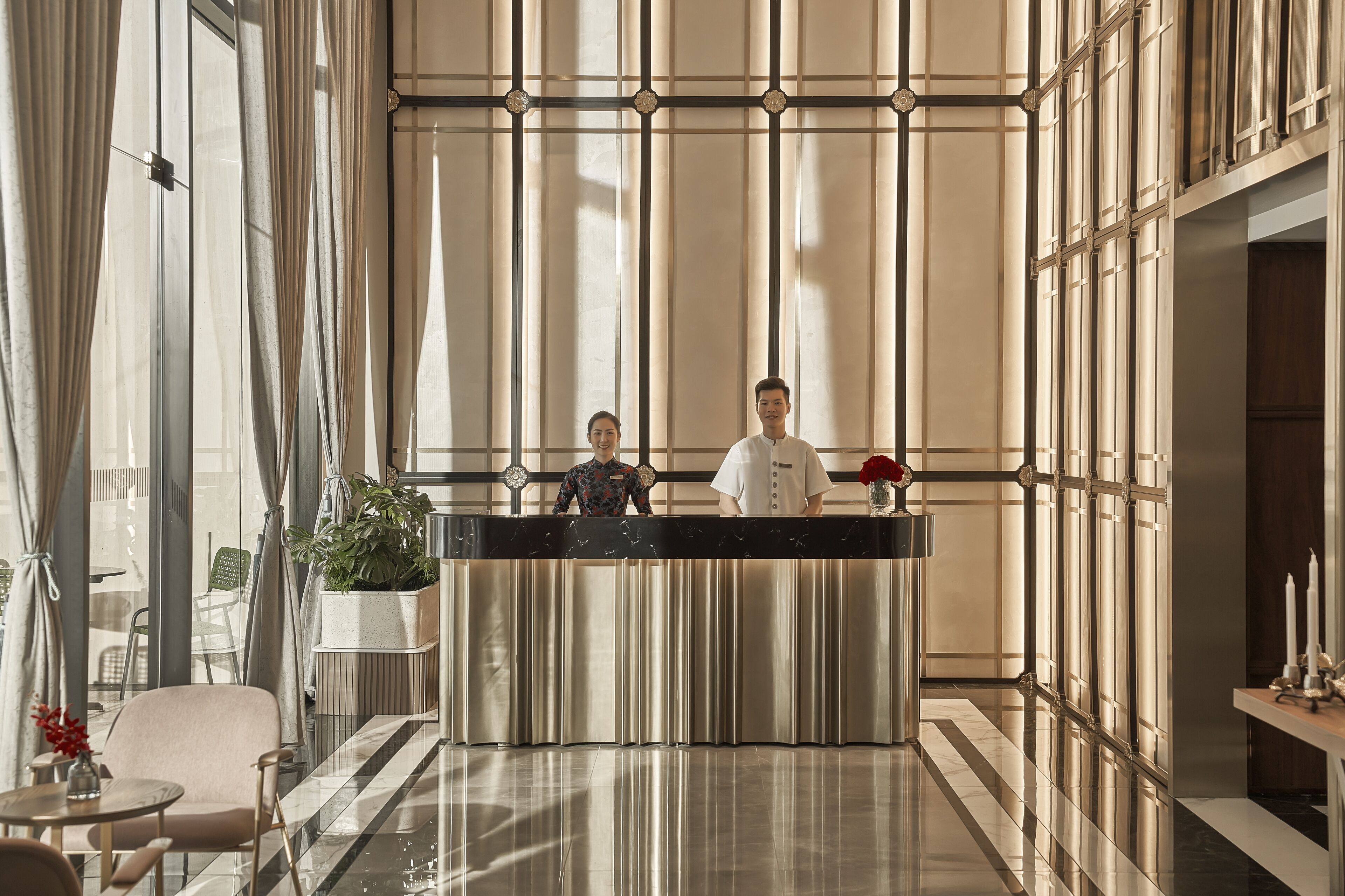 Un área de recepción con diseño moderno, que incluye un mostrador de recepción, zona de estar y ventanas amplias.