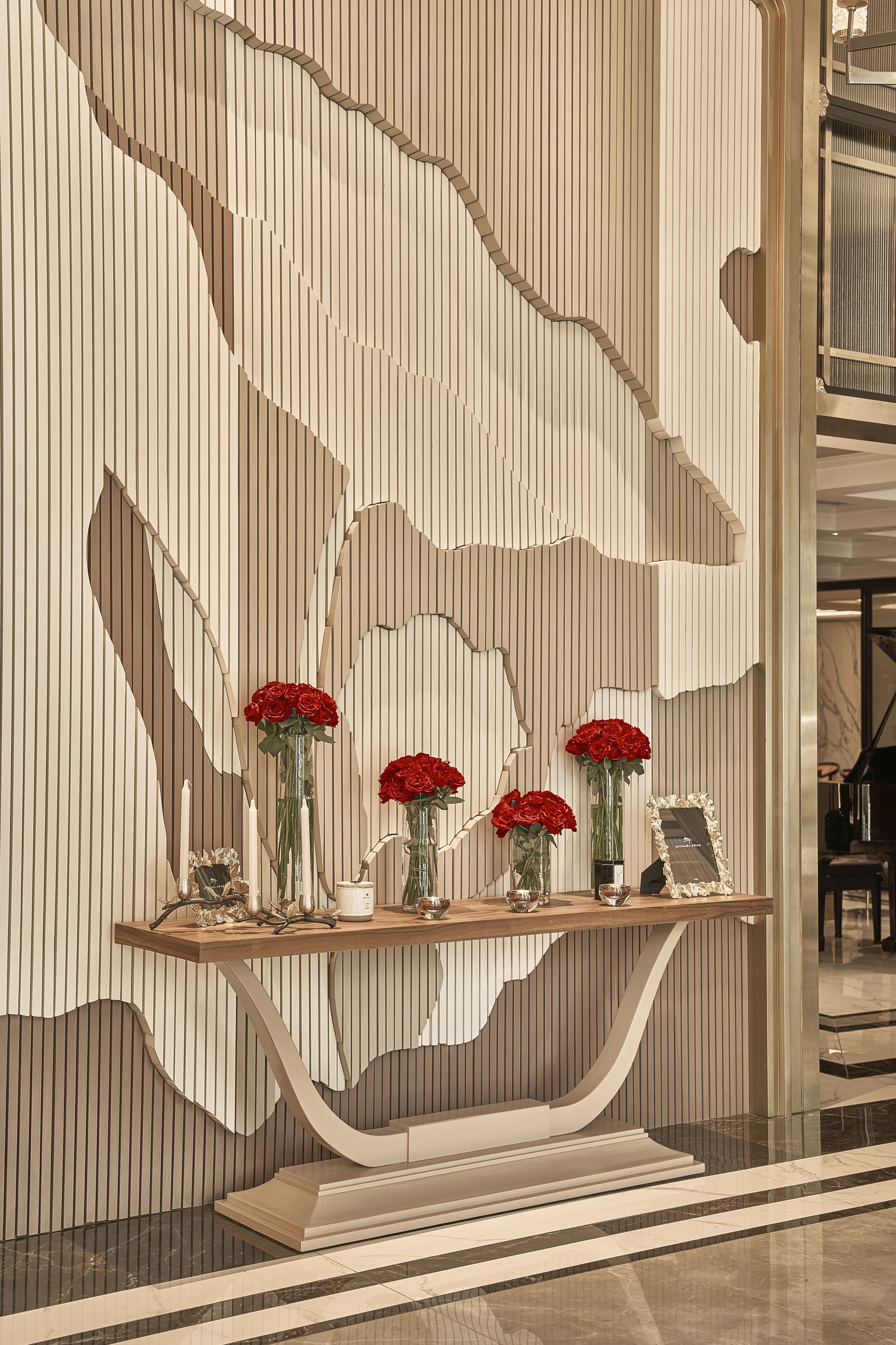 Un interno moderno con una consolle in legno che espone rose rosse e una fotografia incorniciata.