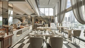 Eine moderne Hotelhalle mit Empfangstresen, einer Sitzecke und einer Treppe, die in eine obere Ebene führt.