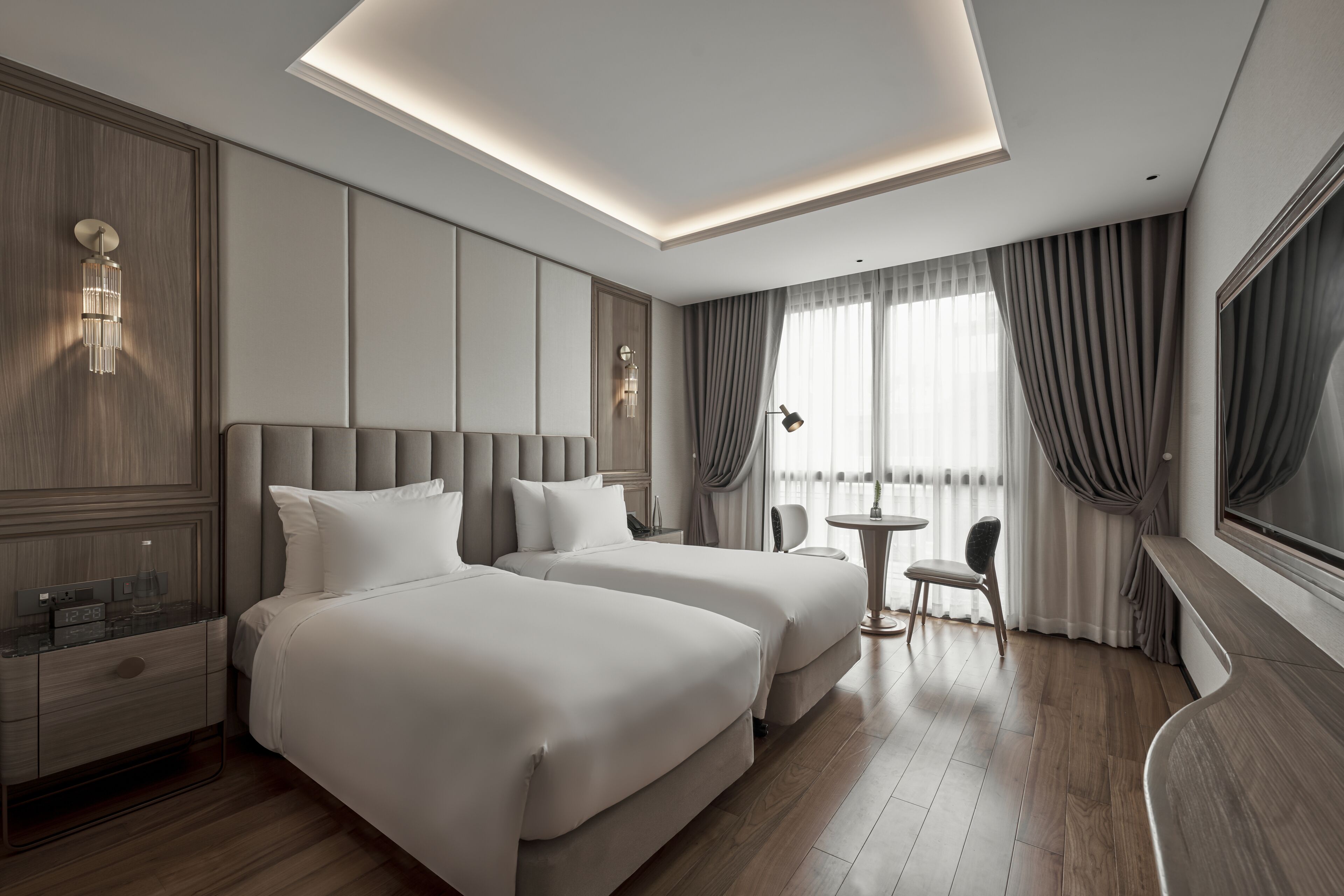 Ein modernes Hotelzimmer mit zwei Betten, einem kleinen Tisch und einem Stuhl.