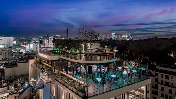 Ein modernes Hotel mit Dachpool, Sitzgelegenheiten im Freien und Blick auf die Stadt.