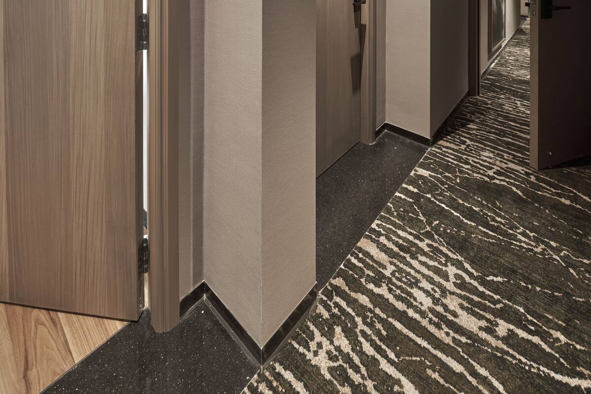 Ein Hotelkorridor mit Teppichboden, Holztüren und einem Schild mit der Nummer 512.