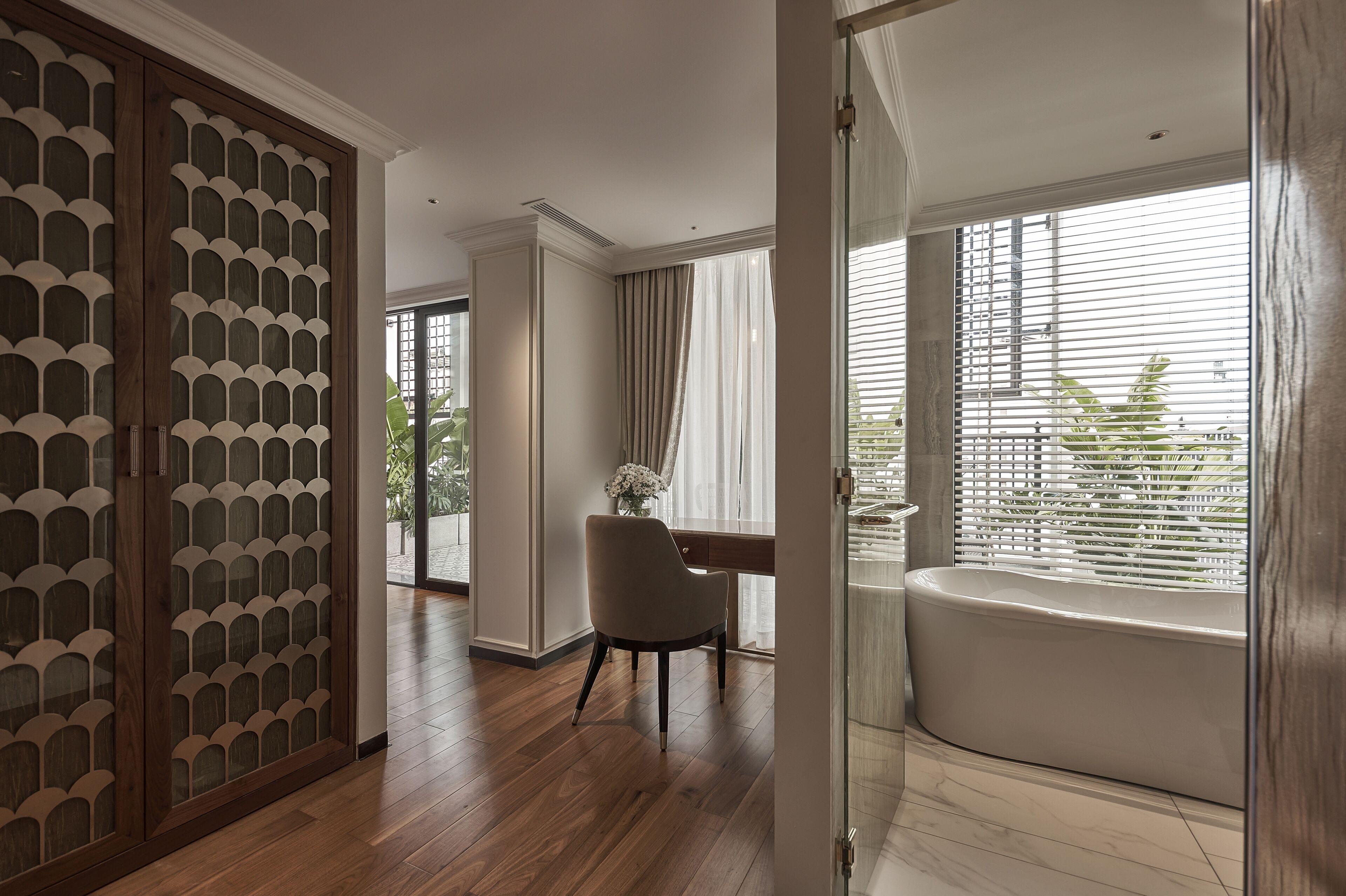 A modern bathroom with a bathtub, a desk, and a chair.