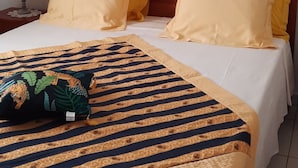 En säng med två kuddar, ett mönstrat överkast och en tavla med ett leopardmotiv på väggen.