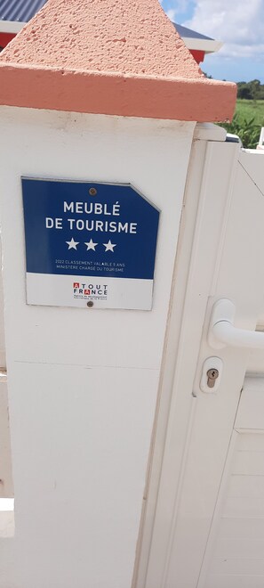 Une enseigne sur un immeuble indique qu’il s’agit d’un « logement meublé de tourisme », avec un fond bleu et des lettres blanches.