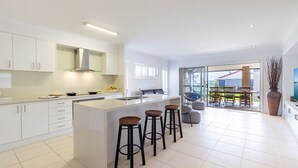 Una cucina moderna con mobili bianchi, un'isola centrale con sgabelli e vista su un patio.