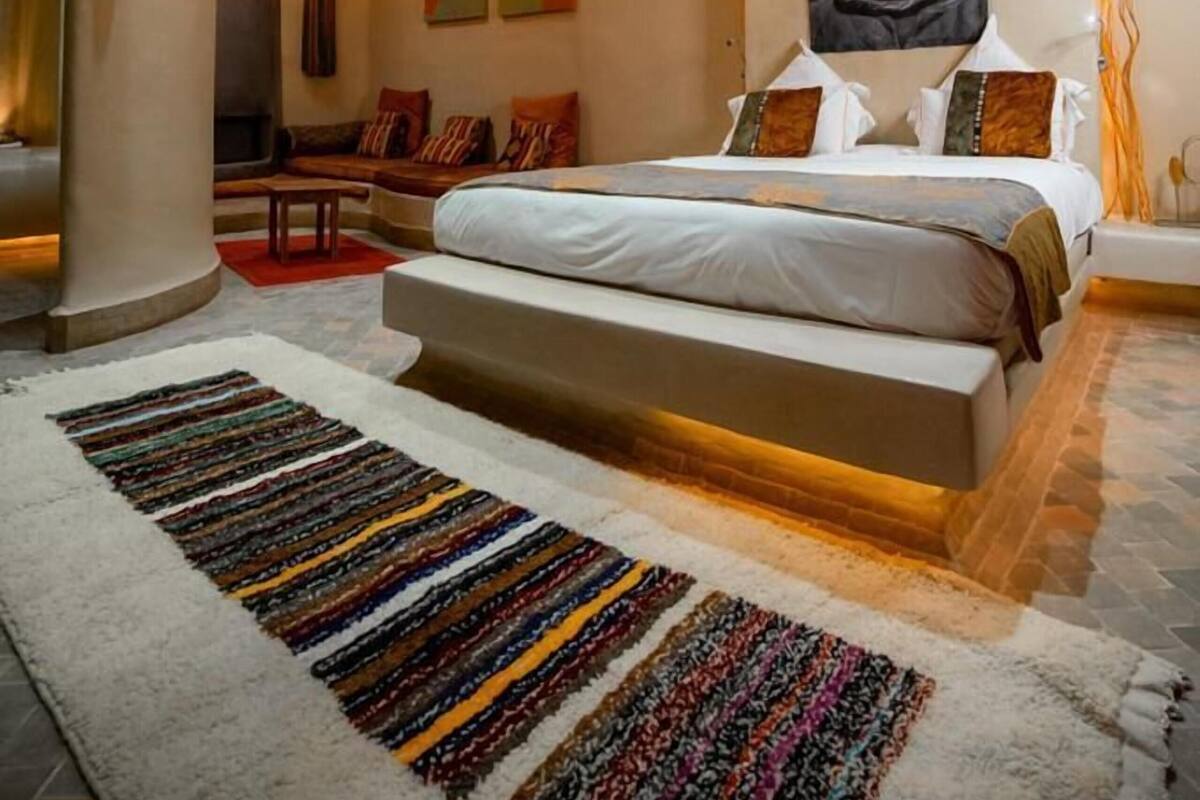 Un dormitorio con cama, candelabro, sofá y alfombra.
