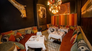 Un restaurante con cabinas y mesas, un candelabro y una decoración de cabeza de jirafa en la pared.