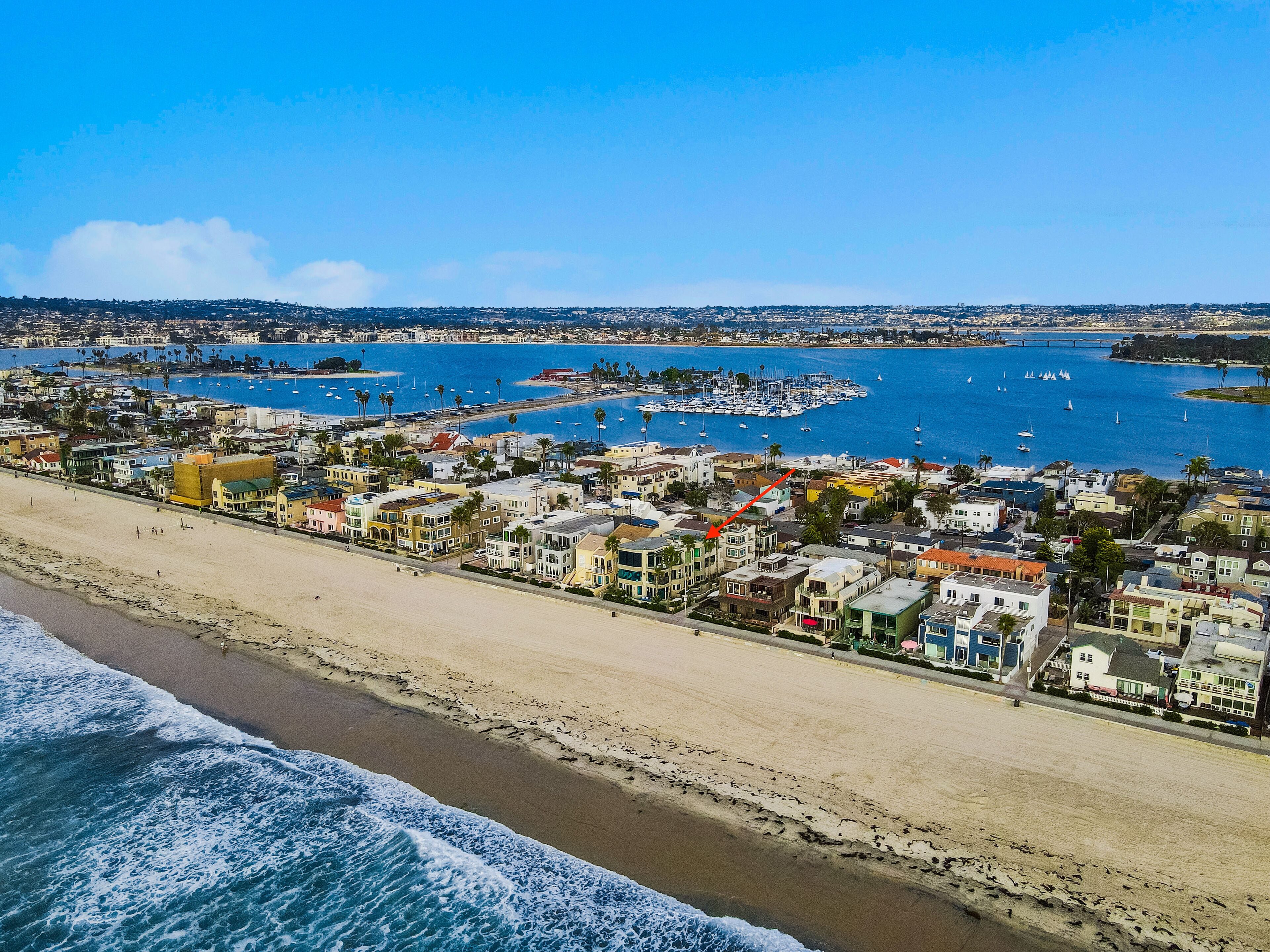 A coastal town with a beach, marina, and residential buildings.