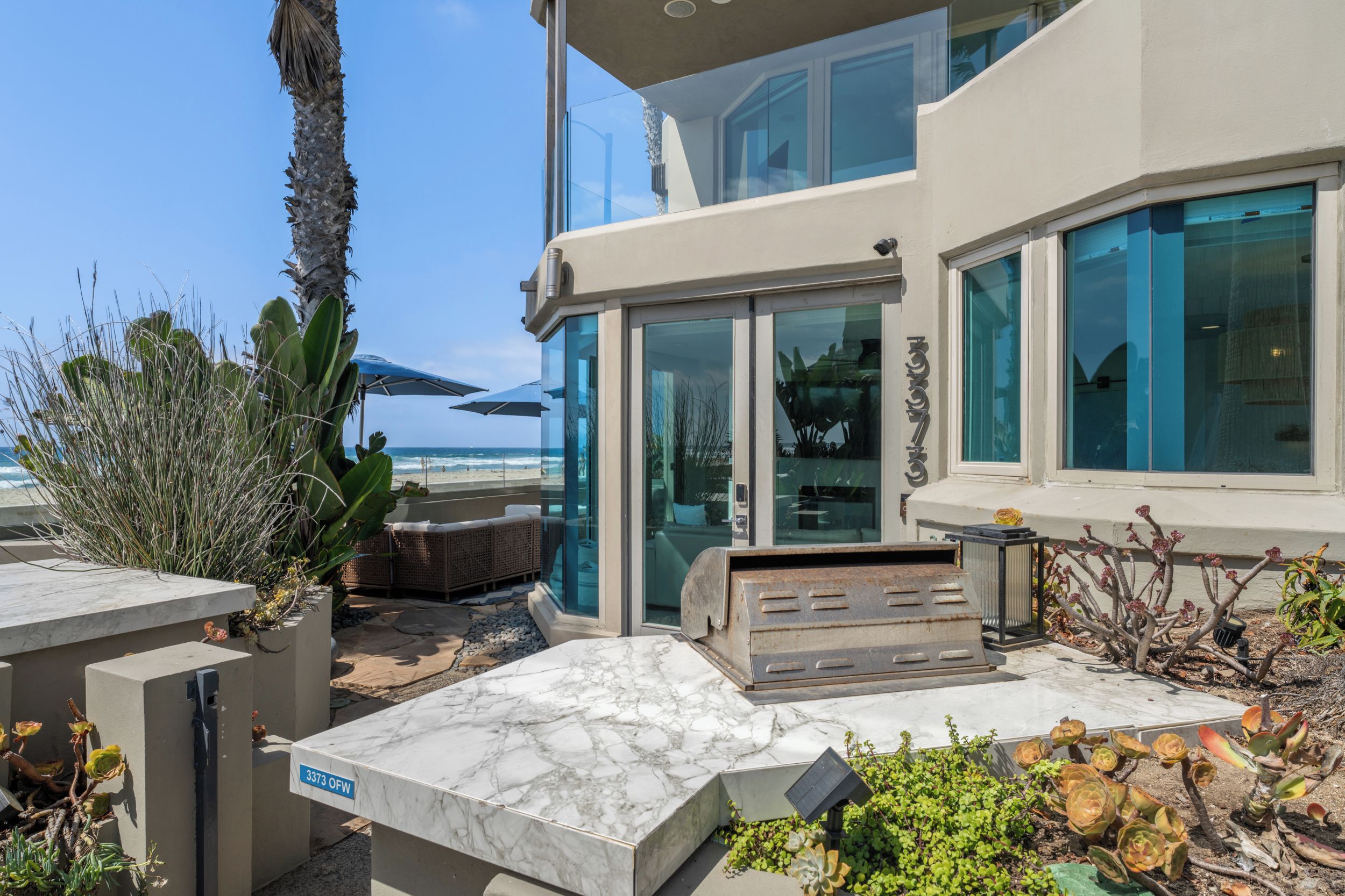 A modern building with a glass facade overlooking a beach.