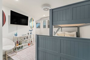 A modern room with a bunk bed, a flat-screen TV, and a shelf with decorative items.