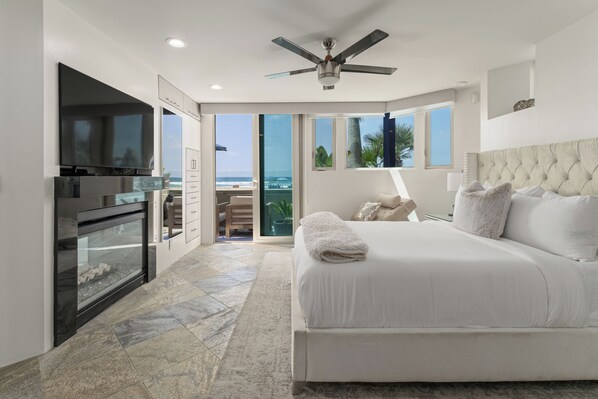 A bedroom with a large bed, a television, and a view of the ocean.