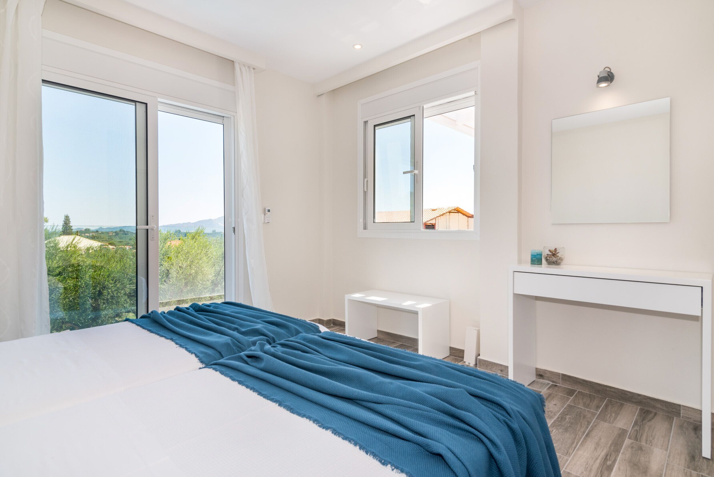 Una camera da letto con un letto grande, un comodino, uno specchio e vista sul verde.