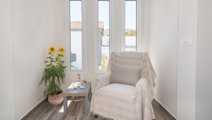 A room with a large window, a chair, a small table, and a potted plant.